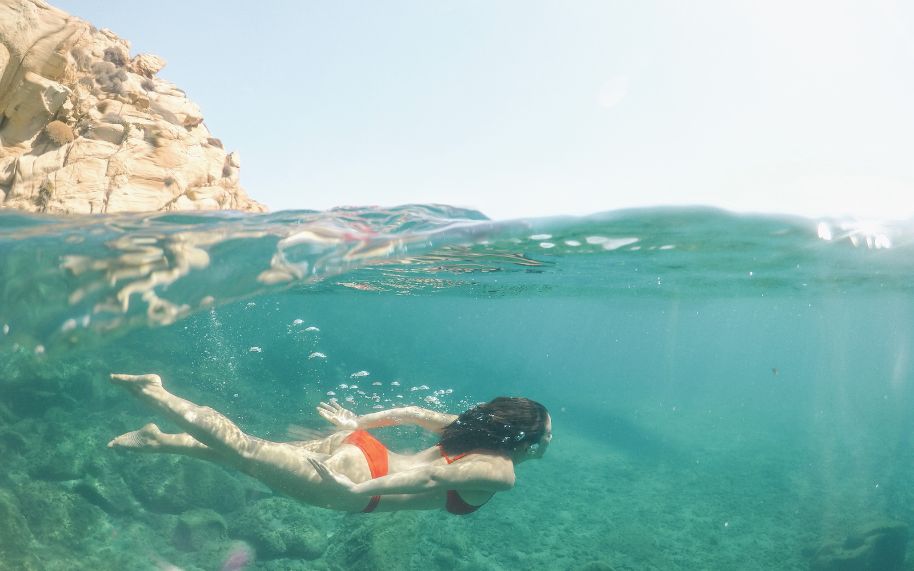Efectos del agua de mar sobre la psoriasis Persona con psoriasis nadando en la playa