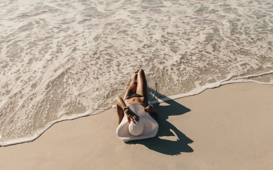 Persona con psoriasis tomando el sol en la playa